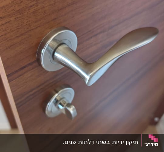 תקריב של ידית מתכת מעוצבת ומנגנון נעילה על דלת פנים בעלת מראה עץ